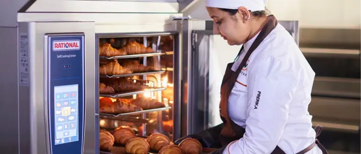 Professional baking student removing freshly baked croissants from a oven during hands-on training