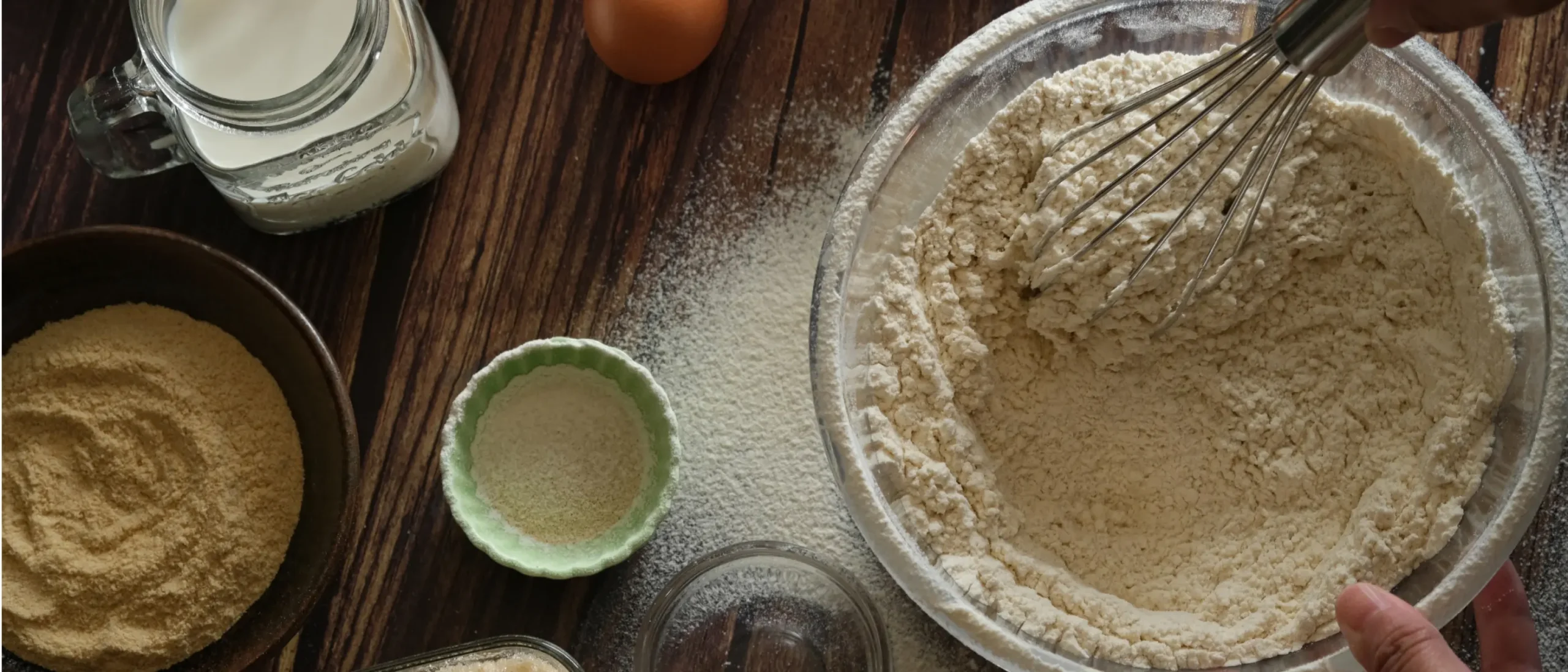whisks flour in a mixing bowl surrounded by baking ingredients, showcasing beginner-friendly baking hacks and tips in baking class
