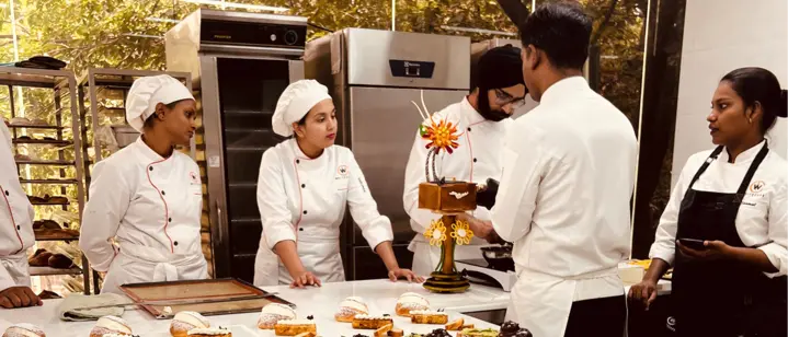 Professional pastry chefs guiding students during a hands-on pastry arts workshop with plated desserts and cake decor