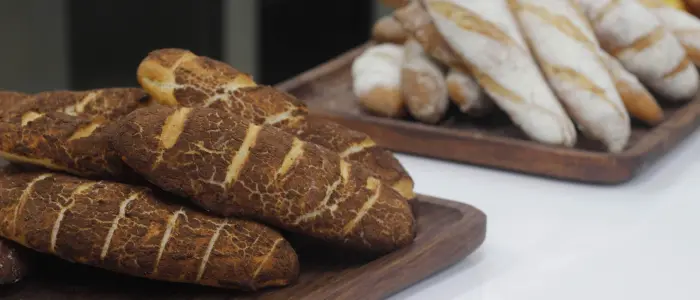 Two wooden trays filled with fresh sourdough bread, showing crisp crusts and simple scoring—ideal for beginners learning to bake at home.